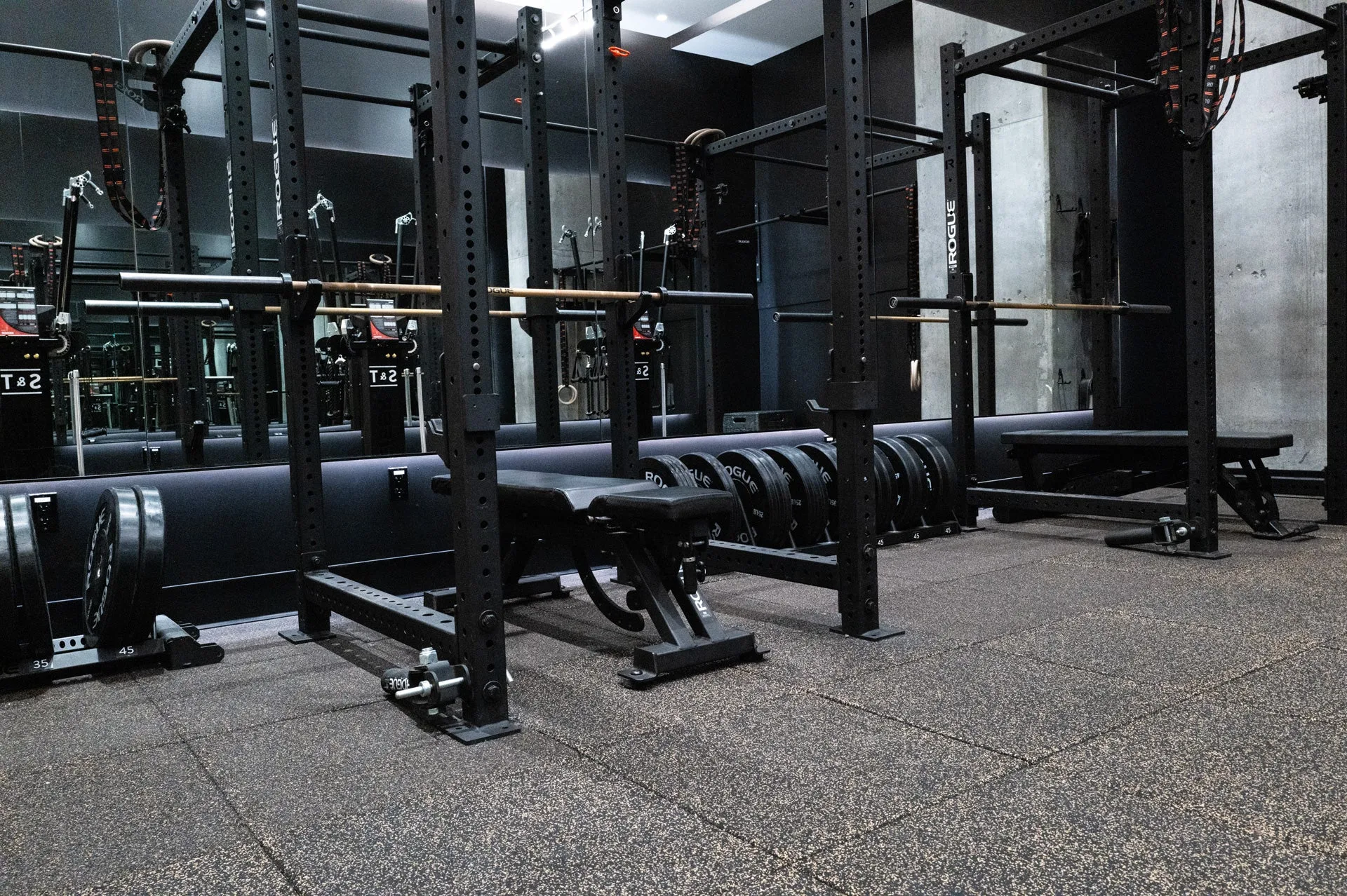 A modern strength training area with racks and benches.