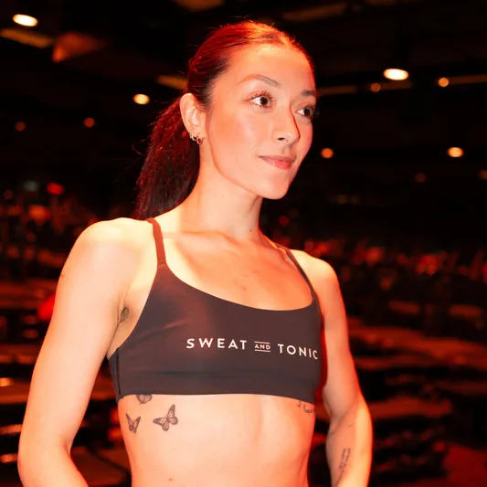 A fitness model wearing a Sweat and Tonic crop top in a gym.