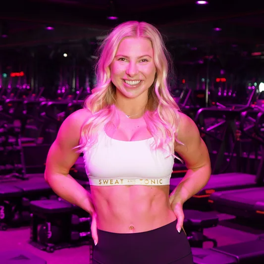 A fitness instructor smiling in a vibrant gym setting.