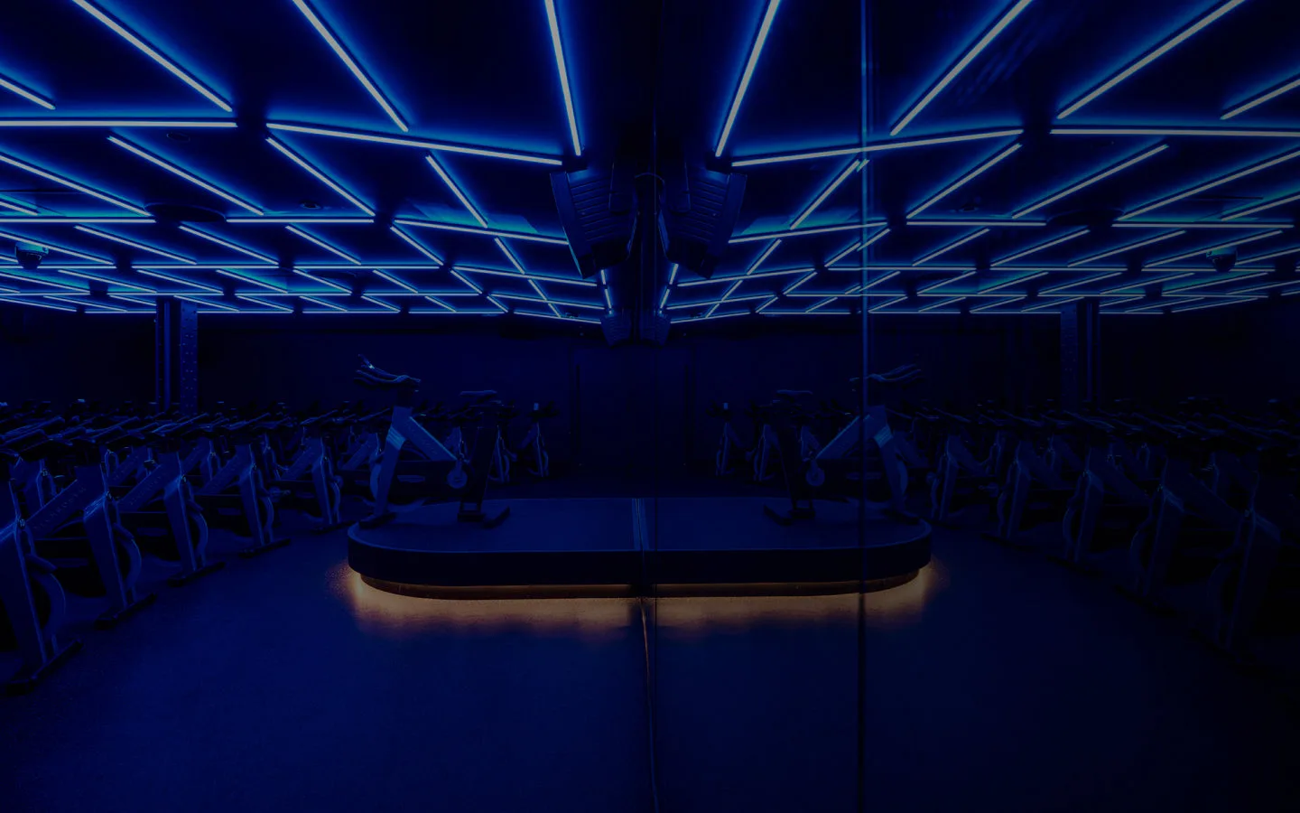 A fitness studio with blue LED lights and stationary bikes.