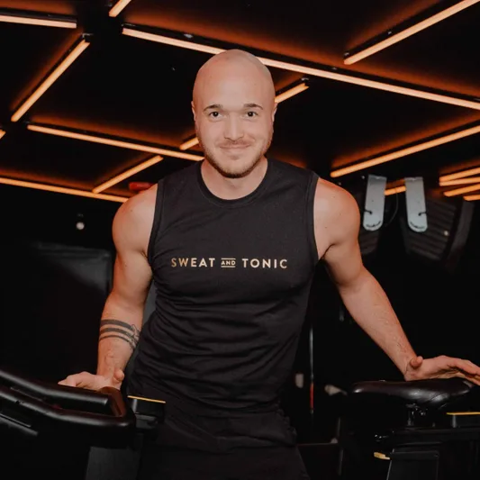 A fitness instructor in a studio wearing a branded shirt.