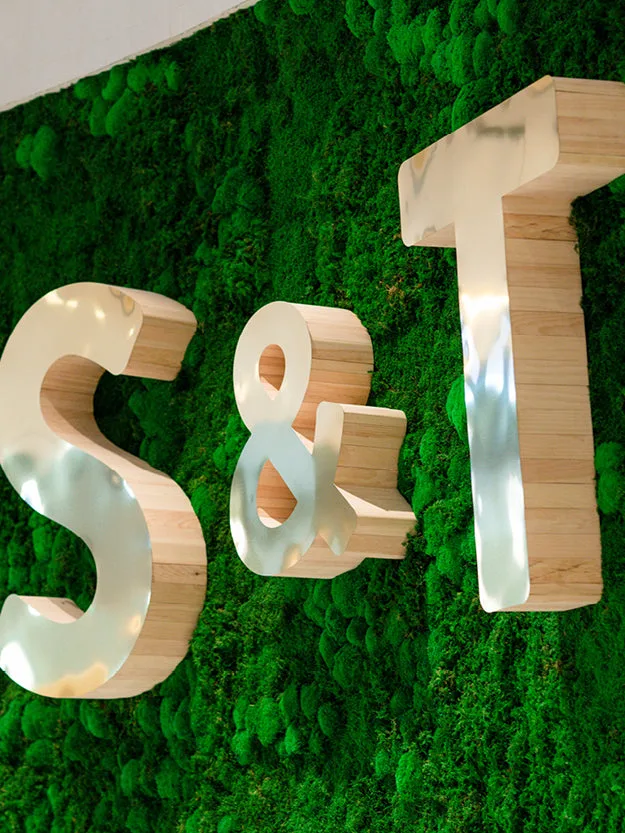 Monogram logo of Sweat and Tonic on a moss wall.