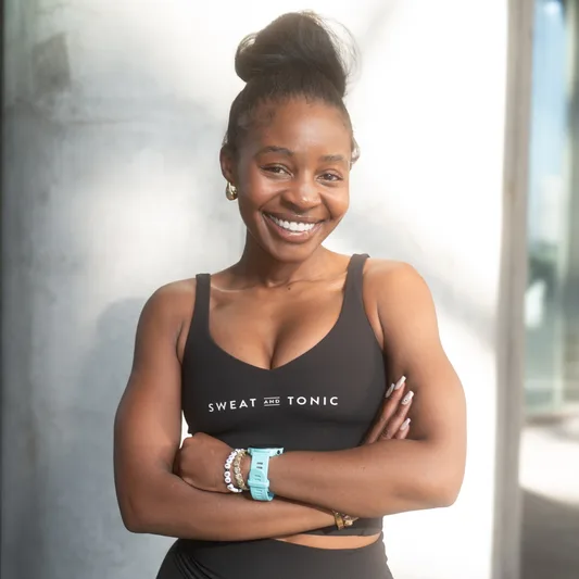 Smiling woman in activewear with arms crossed.