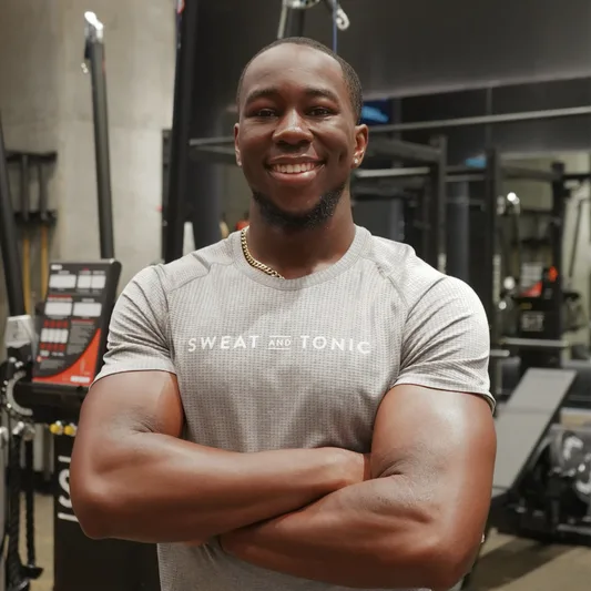 A smiling fitness trainer in a gym setting.