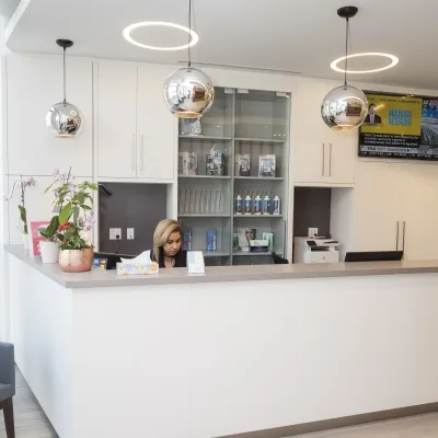 A dental reception area with a staff member and modern decor.