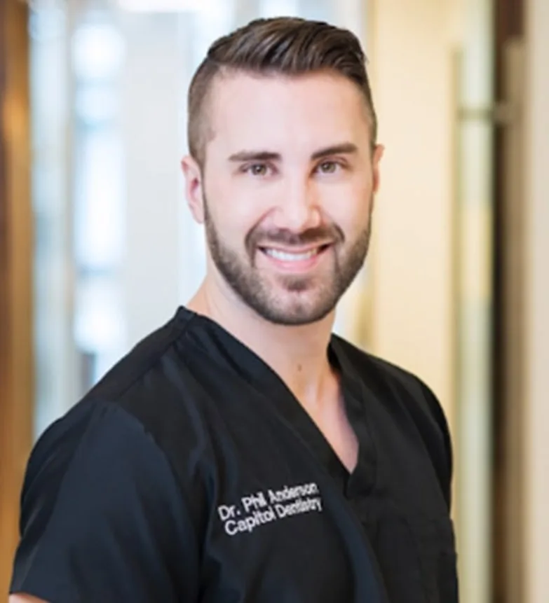 Dr. Phil Anderson in black dental scrubs at Capitol Dentistry.