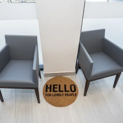 Two gray chairs next to a welcome mat in a dental office.