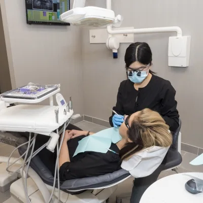 A dental hygienist attending to a patient in a dental office.