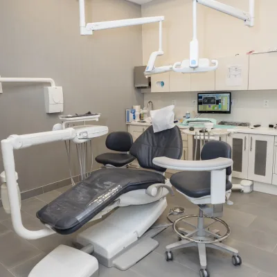 A modern dental treatment room with equipment and a chair.