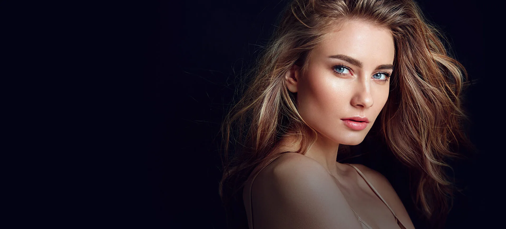 A woman with glowing skin and blue eyes in a dark setting.