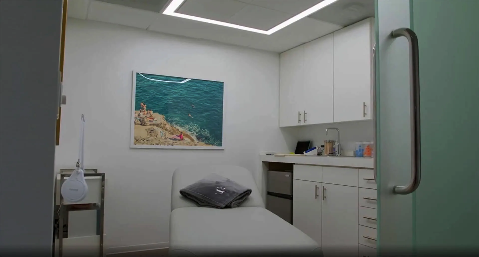 An aesthetic treatment room with modern design and coastal artwork.
