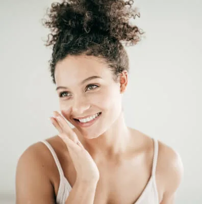 Young woman smiling and touching her face