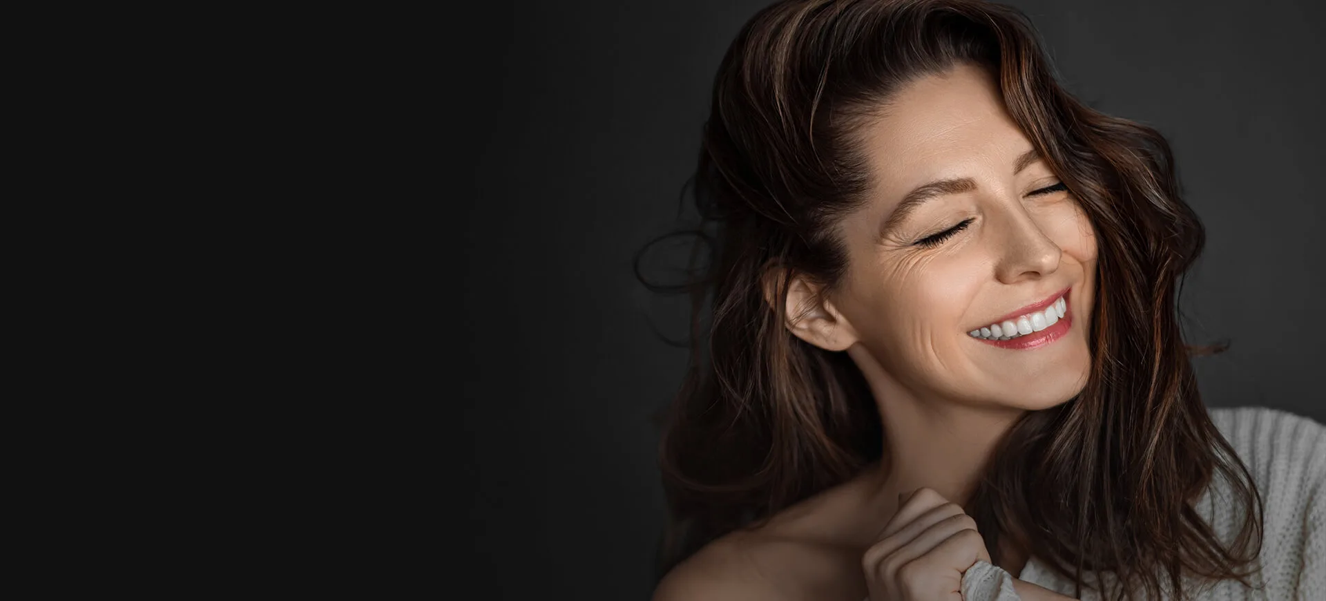 A smiling woman with wavy hair and glowing skin.